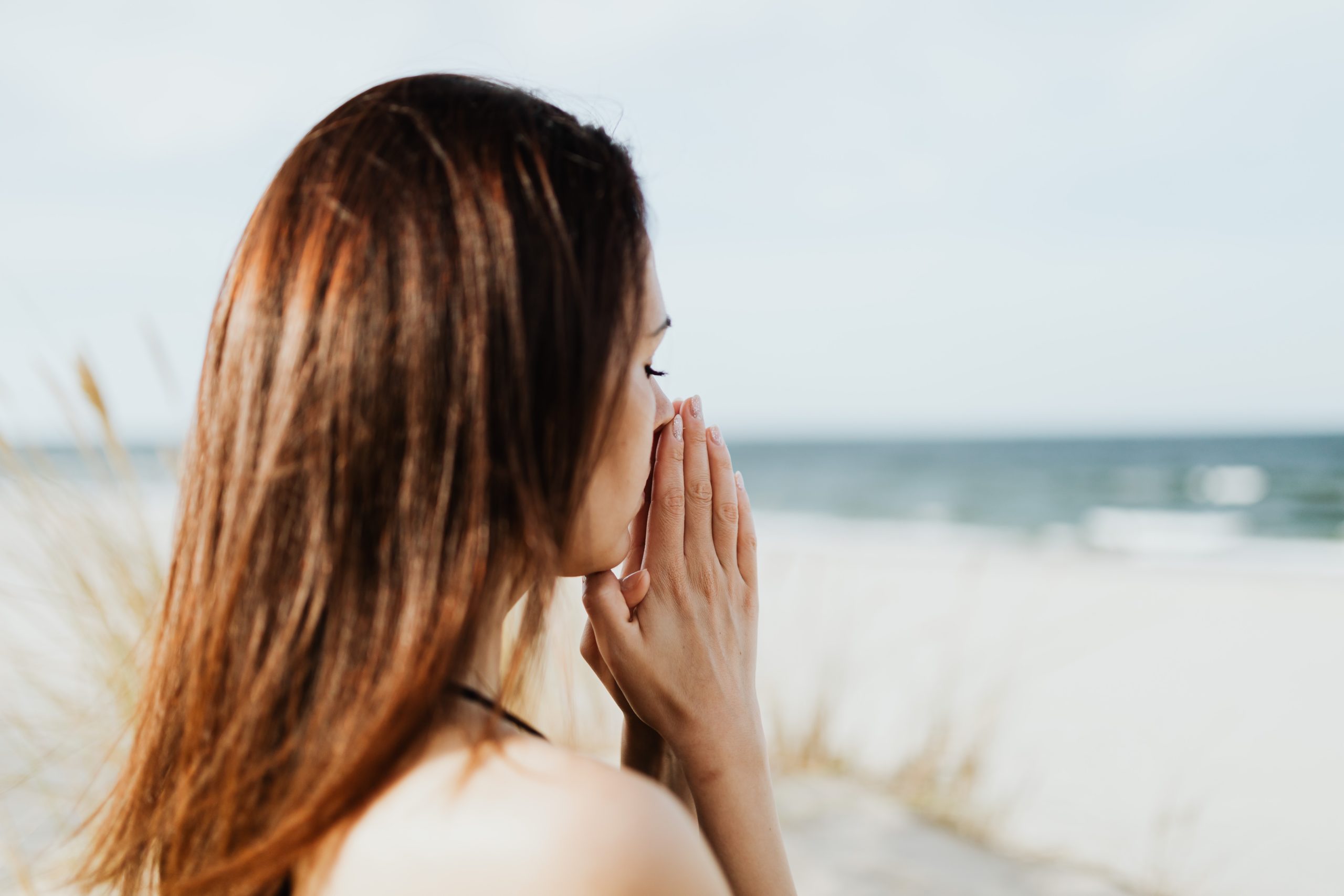 Every Day Trauma: 8 Ways to Feel Better - woman with closed eyes on the edge of a beach